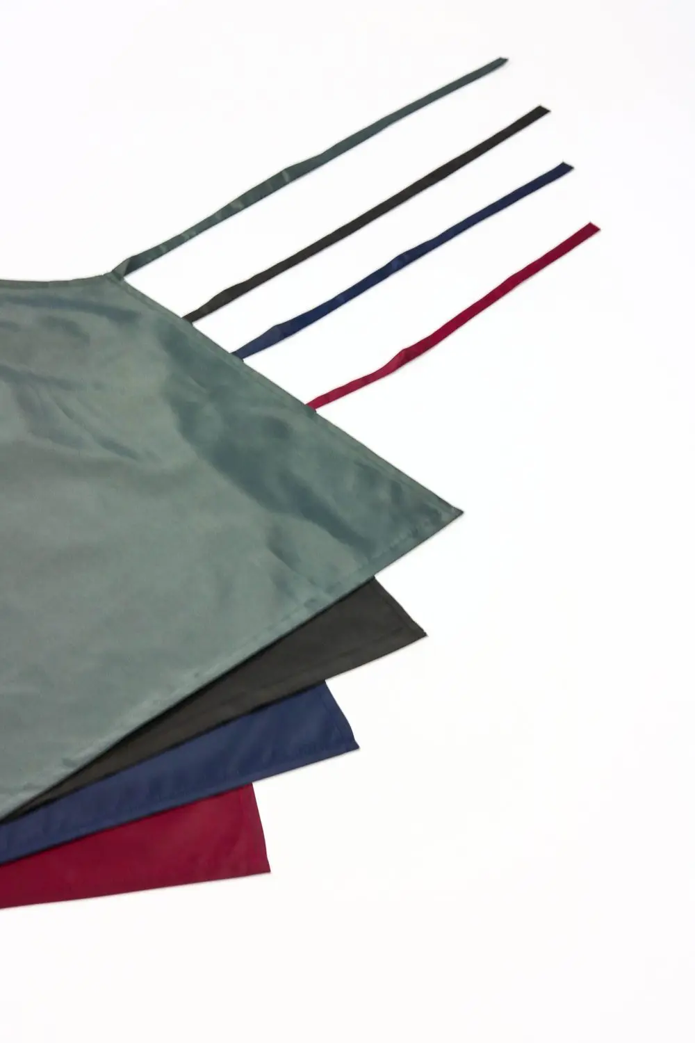 Four Different Coloured Waterproof Bib Aprons Sitting on Top of Each Other